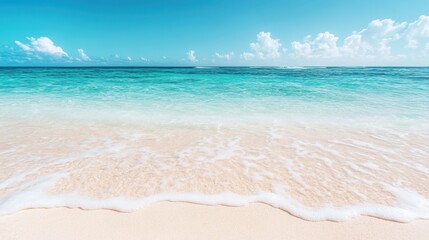 Fototapeta premium An idyllic scene of a turquoise ocean gently kissing the sandy shore under a clear blue sky filled with soft white clouds, epitomizing tranquility and natural beauty.