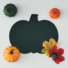 Flat lay of decorative pumpkins, acorns, autumn leaves and pumpkin shaped cutout. Cozy seasonal concept for fall backgrounds, Thanksgiving themes and harvest celebrations. Creative copy space.