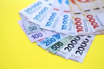 Argentine pesos money bills in big amount lies on yellow color table close up