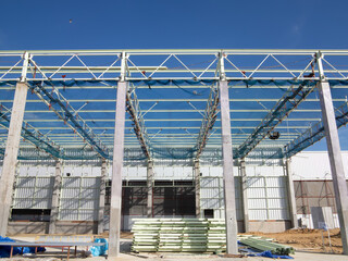 Roof under construction in construction site . To election or assembly frame truss, steel structure for cover factory warehouse building. Include scaffolding and safety net to prevent worker falling.