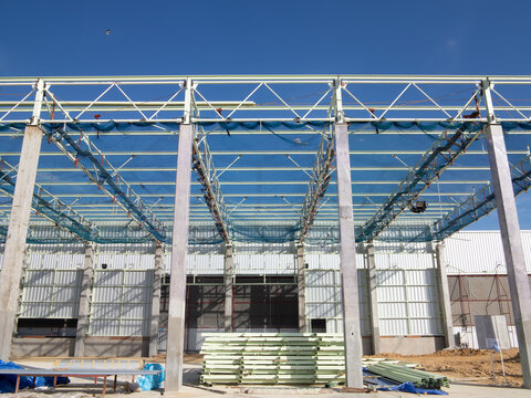 Roof under construction in construction site . To election or assembly frame truss, steel structure for cover factory warehouse building. Include scaffolding and safety net to prevent worker falling.