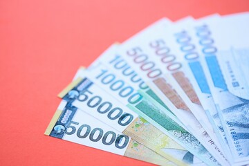 South Korean won money bills in big amount lies on red color table close up