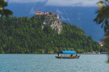  Traditional pletna boats with tourists on Lake Bled, Slovenia, with Bled Castle visible on the...
