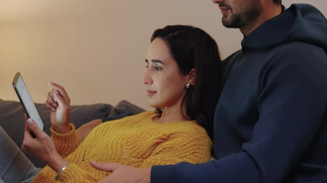 hispanic Couple using digital tablet and browsing online shopping at home during a night promotion