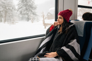 Young woman traveling by train and looking out the window .