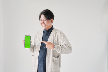 A man is holding a green phone and pointing to it. He is smiling. The phone is green and has a green screen