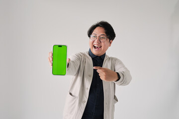 A man is holding a green phone and pointing to it. He is smiling. The phone is green and has a green screen