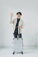 A man is standing next to a suitcase and waving