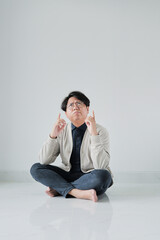 A man is sitting on the floor with his hands in the air