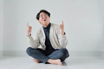 A man is sitting on the floor with his hands up in the air