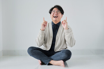 A man is sitting on the floor with his hands up in the air