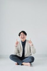 A man is sitting on the floor with his hands up in the air