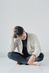 A man is sitting on the floor with his head in his hands