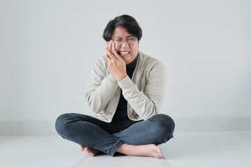 A man is sitting on the floor with his hands on his face