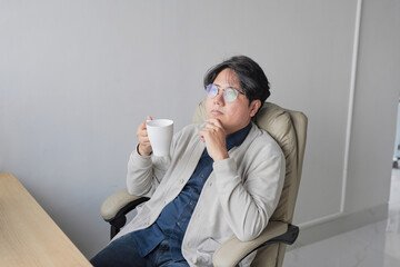 A man is sitting in a chair with a cup in his hand