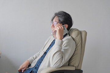 A man is talking on his cell phone while sitting in a chair