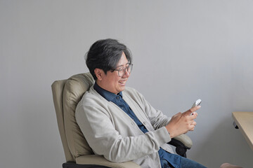 A man is sitting in a chair and holding a cell phone