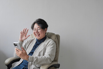 A man is sitting in a chair and holding a cell phone