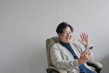A man is sitting in a chair and holding a cell phone