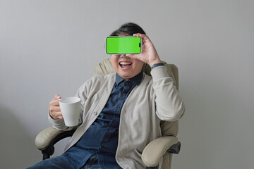 A man is sitting in a chair holding a green phone