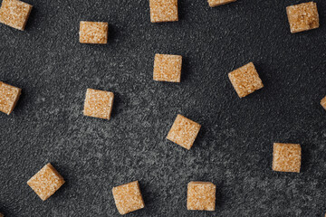Brown sugar cubes scattered on a dark textured surface in a kitchen setting