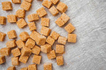 Brown sugar cubes scattered on textured linen fabric in a cozy kitchen
