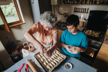 A grandmother and her grandson bake pastries together, sharing family traditions and creating warm...