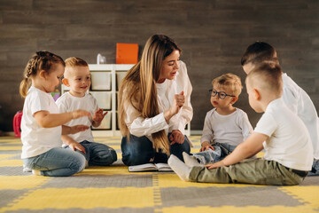 On the floor, learning new words. Children in kindergarten with their teacher