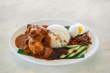 Delicious nasi lemak with chicken rendang, sambal, rice, egg, peanuts, anchovies, and cucumber...