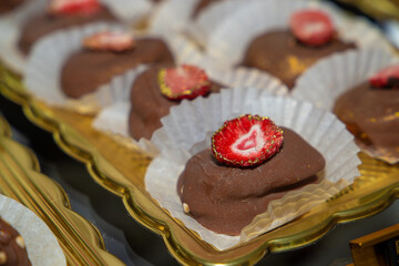 Luxurious handmade decorative chocolates in a display case of assorted pralines with selective accent.