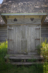 A wooden outhouse with a roof and a door with a heart on it