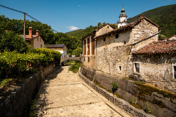 Charming Townscape Of Vipava With Castle View: Colorful Historic Houses And Church Tower Nestled Below Forested Hills With Distant Castle Ruins Under A Clear Blue Sky In Western Slovenia
