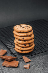 Freshly baked chocolate chip cookies stacked on a cooling rack in a kitchen