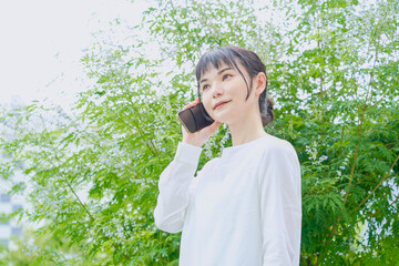 スマートフォンで電話をする屋外での爽やかな30代女性