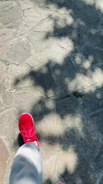 inquadratura da sopra di persona che cammina, primo piano di gambe e piedi su una pavimentazione in pietra