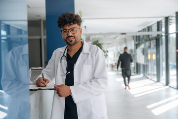 Black notepad in hands. Doctor is indoors in the modern building