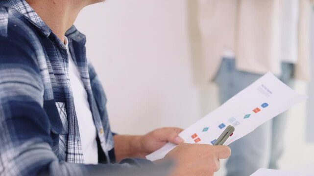 Senior programmer planning software development with flowchart and system process documentation at office