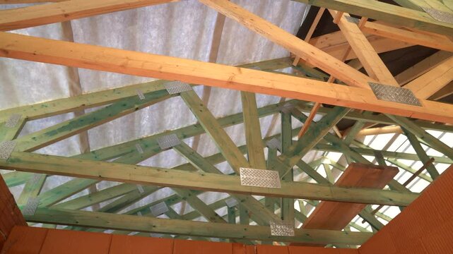 Wooden roof trusses and beams installed under membrane in unfinished brick house