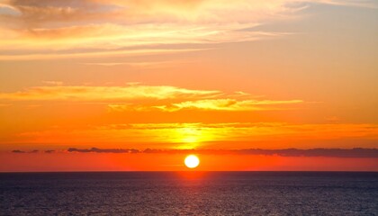 Fototapeta premium Vivid sunset over a calm ocean, painted with hues of orange, red, and gold creating a peaceful mood.