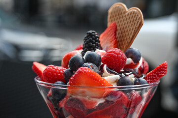 Ice cream sundae with fruits, blueberries and strawberries in a street cafe, copy space, selected focus
