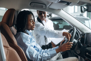 In brown colored seat, trying vehicle. Man and woman are in the automobile