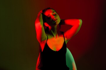 Woman poses dramatically in contrasting red and green lighting, showcasing bold expressions and...