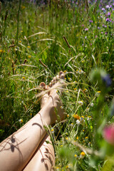 Woman relaxing with bare feet in wildflower meadow