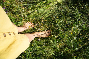 Woman standing barefoot in wild chamomile field enjoying nature