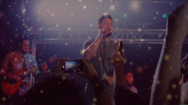 Singer entering concert stage singing and guitarist strumming particles floating engaging crowd