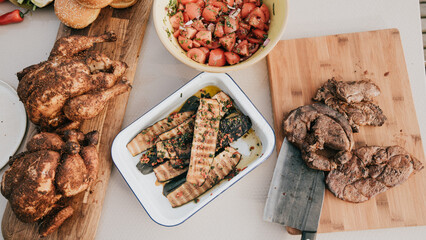 A table with a variety of meats and vegetables, including chicken, beef, and zucchini