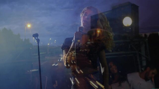 Female singer grabbing mic and singing at concert with highway projection and band emerging