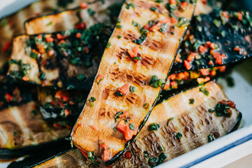 A plate of grilled vegetables with a lot of seasoning. The vegetables are cut into thin strips and...
