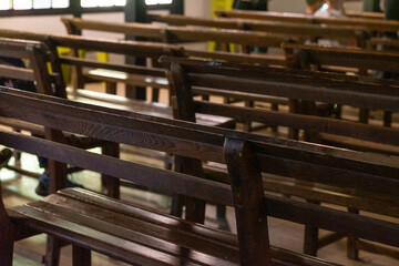 A dimly lit interior of a vintage theater, featuring long rows of aged wooden seats arranged in perfect symmetry. The soft ambient light highlights the texture of the polished wood and evokes a nostal