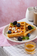 Belgian whole wheat waffles with blueberry on a white table rose background. Breakfast time. Vertical